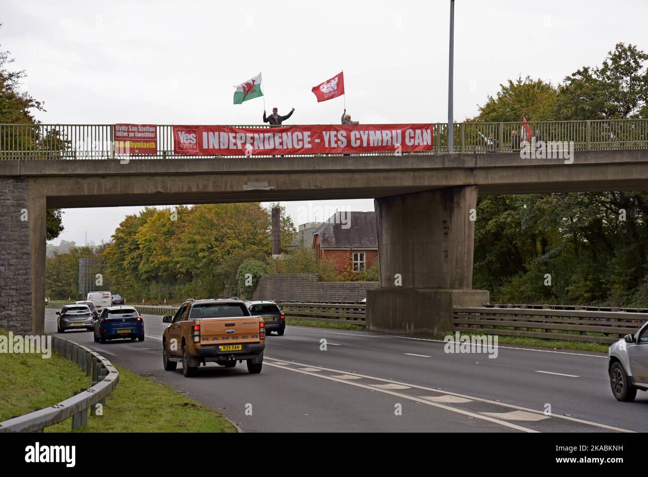 Wahlkämpfer für eine walisische Unabhängigkeit Ja stimmt mit Transparenten und walisischen Flaggen auf der Straßenbrücke A40 in Carmarthen, Wales Stockfoto