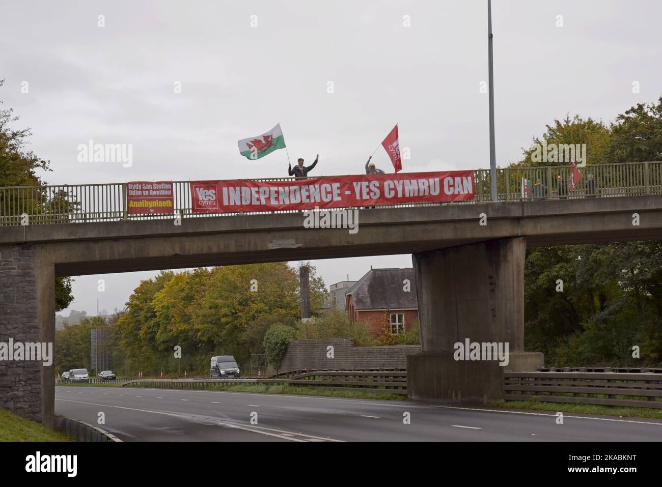 Wahlkämpfer für eine walisische Unabhängigkeit Ja stimmt mit Transparenten und walisischen Flaggen auf der Straßenbrücke A40 in Carmarthen, Wales Stockfoto