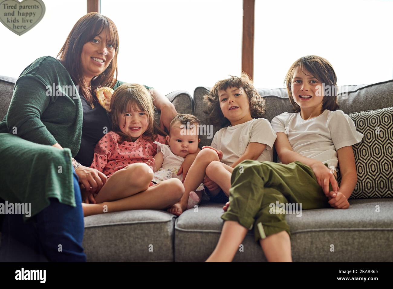 Waren eine große und gesegnete glückliche Familie. Porträt einer Mutter, die sich zu Hause mit ihren vier kleinen Kindern verbunden hat. Stockfoto