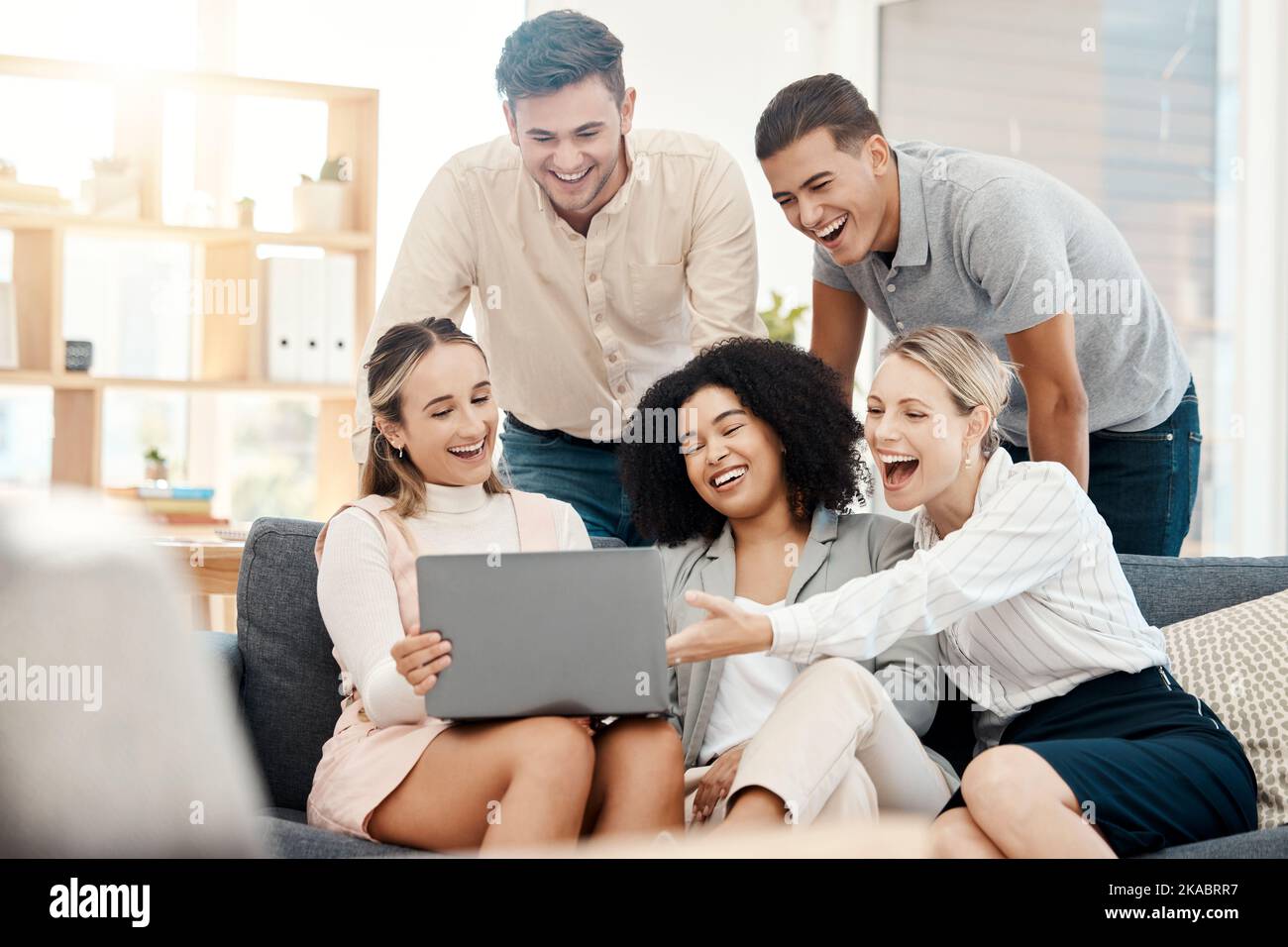 Team, Erfolg und Zusammenarbeit mit Laptop in Meetings, glücklicher Büroumgebung und Gemeinschaft. Geschäftsleute lachen, sehen sich Videos online an und Stockfoto