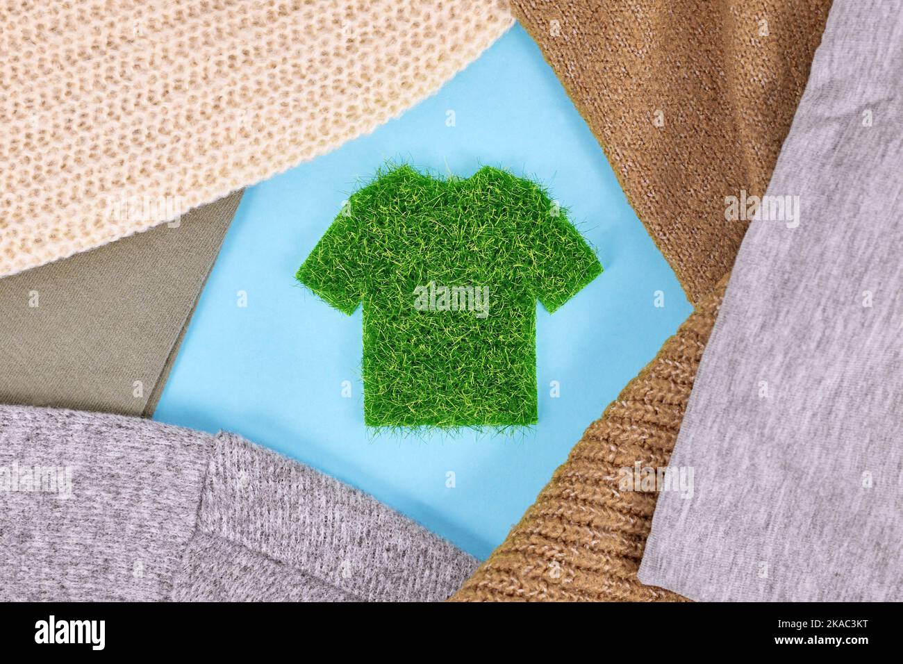 Konzept für umweltfreundlich produzierte Kleidung mit Hemd aus Gras, umgeben von Pullovern Stockfoto