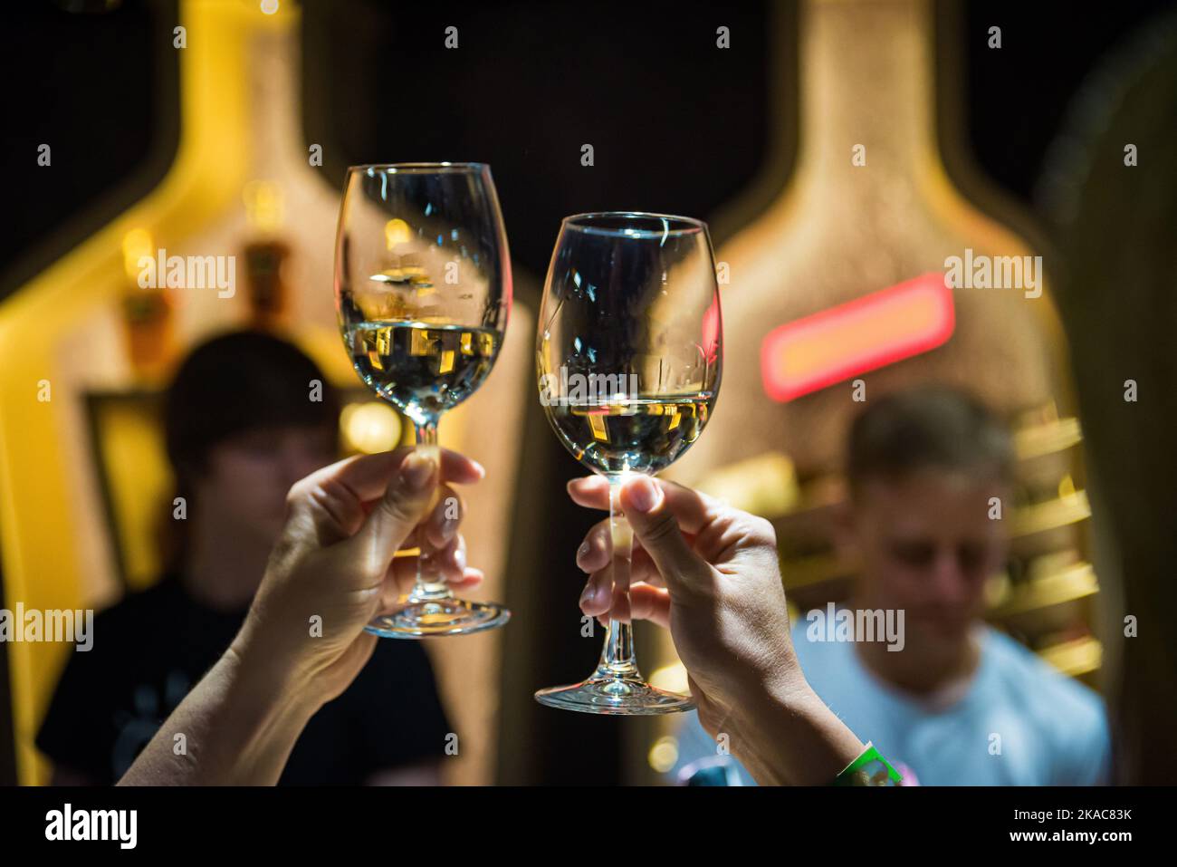 Menschen klirren Gläser mit Wein auf der Sommerterrasse des Cafés oder Restaurants, Glasflasche in den Händen verschiedenen Hintergründen Stockfoto