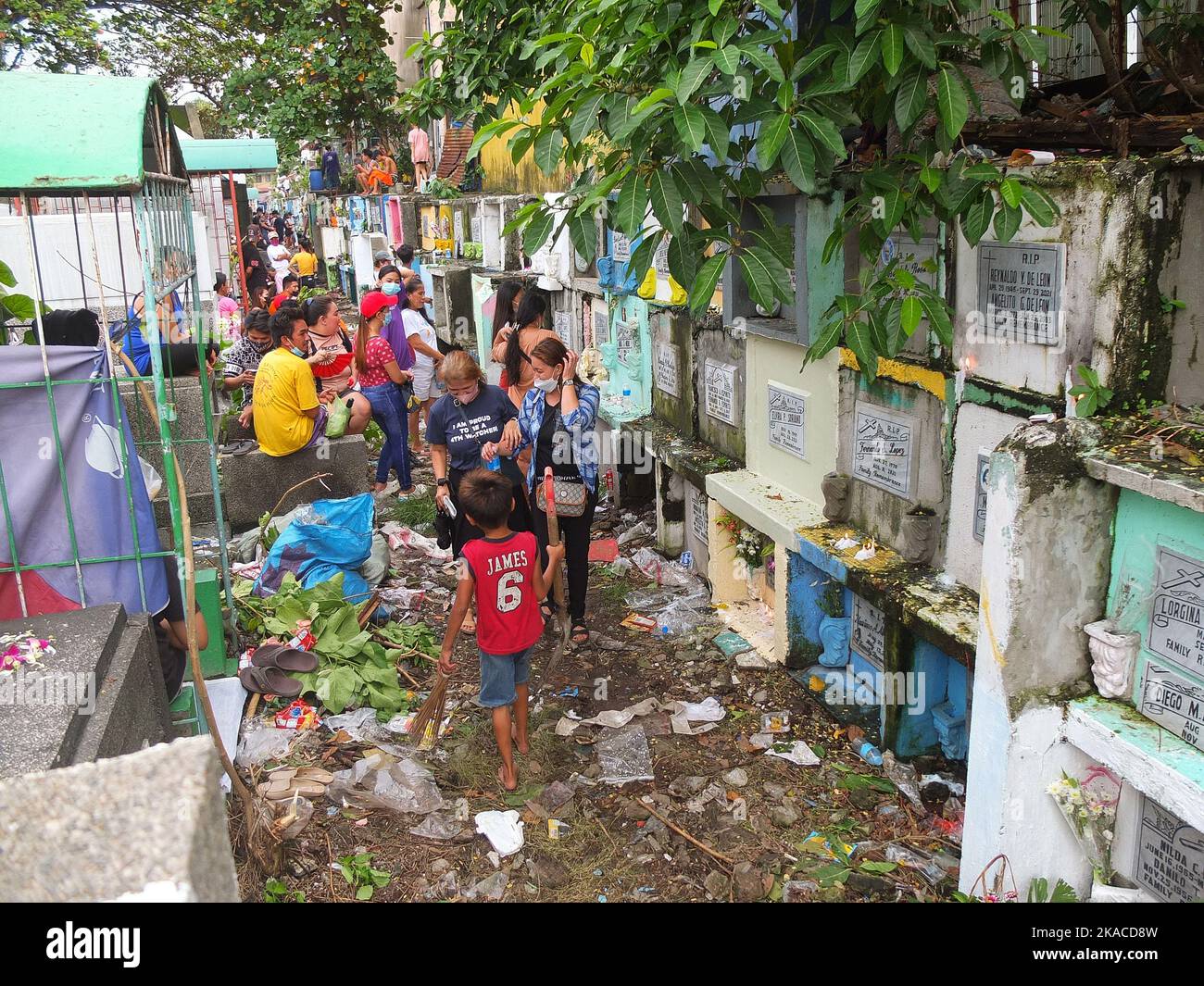 Caloocan City, Philippinen. 01.. November 2022. Die Besucher des Friedhofs laufen entlang eines Müllstapels, um ihren Toten während des Allerheiligen-Tages ihre Achtung zu erweisen. Filipinos strömen nach zwei Jahren der Covid-19-Pandemie auf Friedhofs, da sich die Einschränkungen langsam lockern. Die Tradition, Blumen zu bringen, Kerzen anzuzünden und sogar Nahrung an der Begräbnisstätte ihrer verstorbenen Lieben anzubieten. (Foto: Josefiel Rivera/SOPA Images/Sipa USA) Quelle: SIPA USA/Alamy Live News Stockfoto