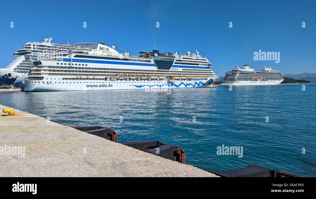 Riesige Kreuzfahrtschiffe, die in Korfu Griechenland vor Anker liegen, zeigen deutlich die unterschiedlichen Größen der Schiffe, die durch die Ozeane und Meere fahren Stockfoto