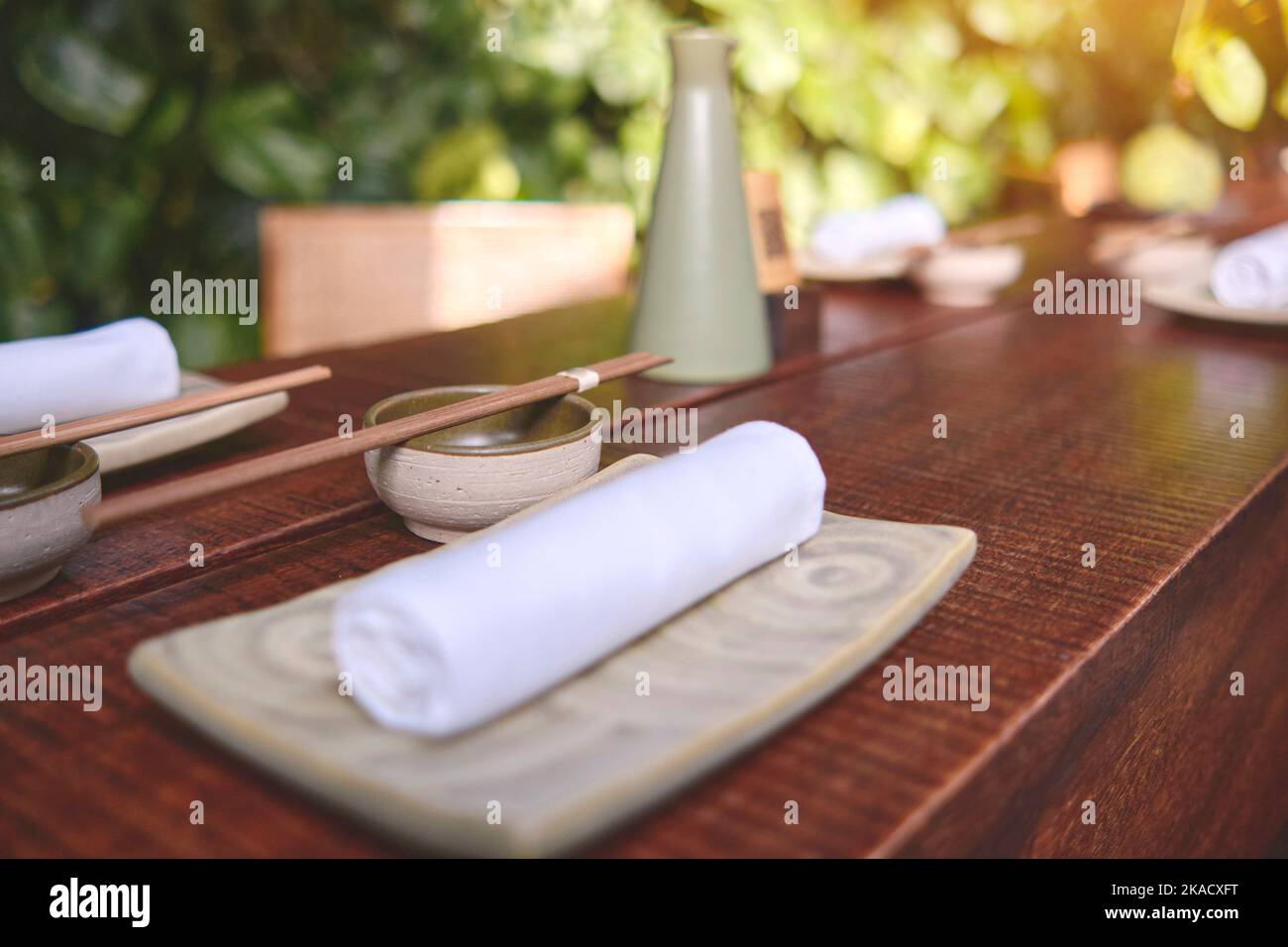 Japanisches Restaurant in traditionellem Stil, leerer Teller auf Matte in der Nähe des Essstäbchen-Behälters, Selective Focus Stockfoto