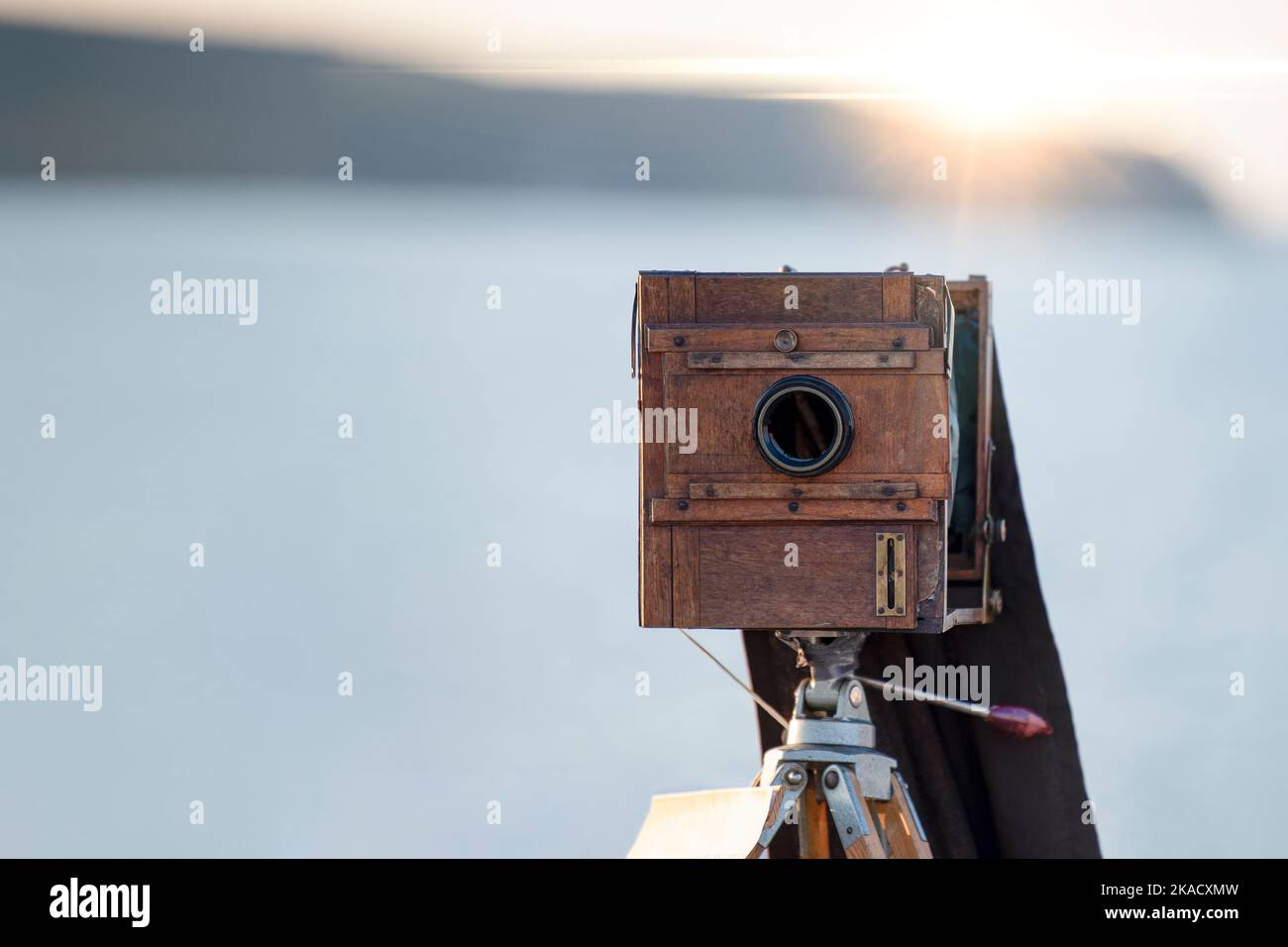 Alte Holzkamera. Alte Kamera auf einem Stativ. Sonnenuntergang am Meer Stockfoto