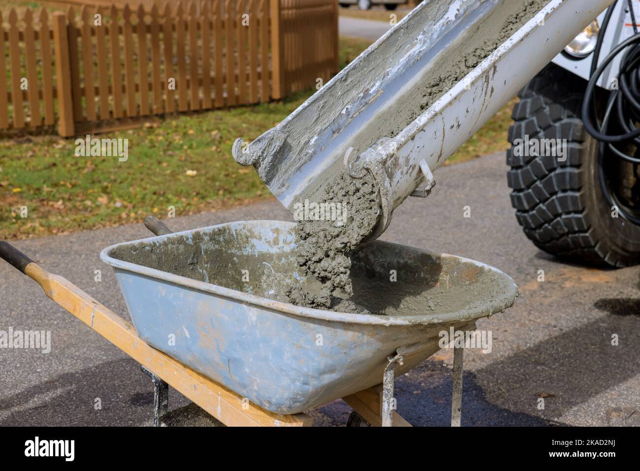 Auf der Baustelle gießt der Betonmischer feuchten Zement in die Schubkarre Stockfoto