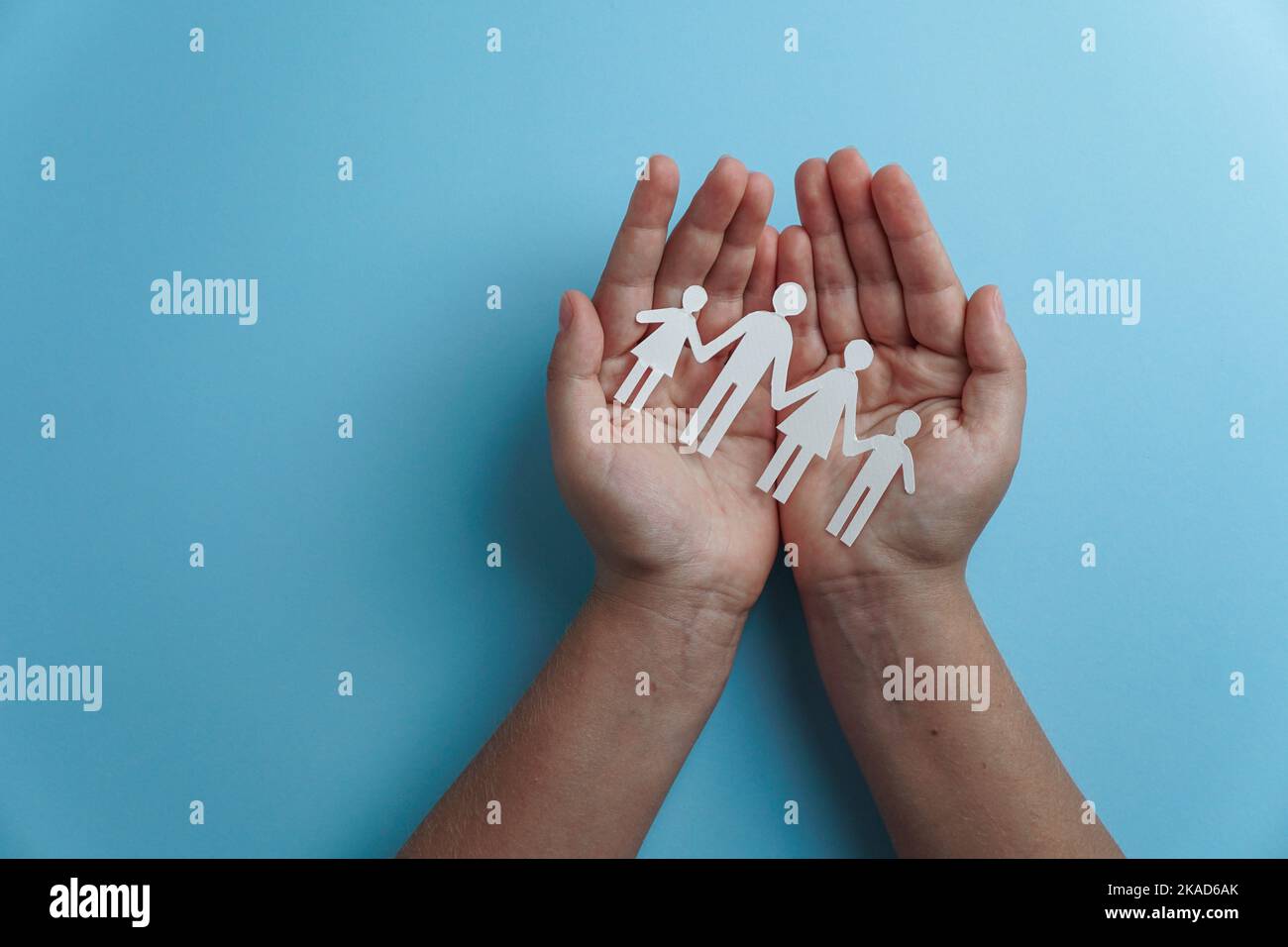 Hände mit Papier Familienausschnitt, Lebensversicherung, soziales Distanzierungskonzept, covid19, auf blauem Hintergrund, Familienschutz Stockfoto