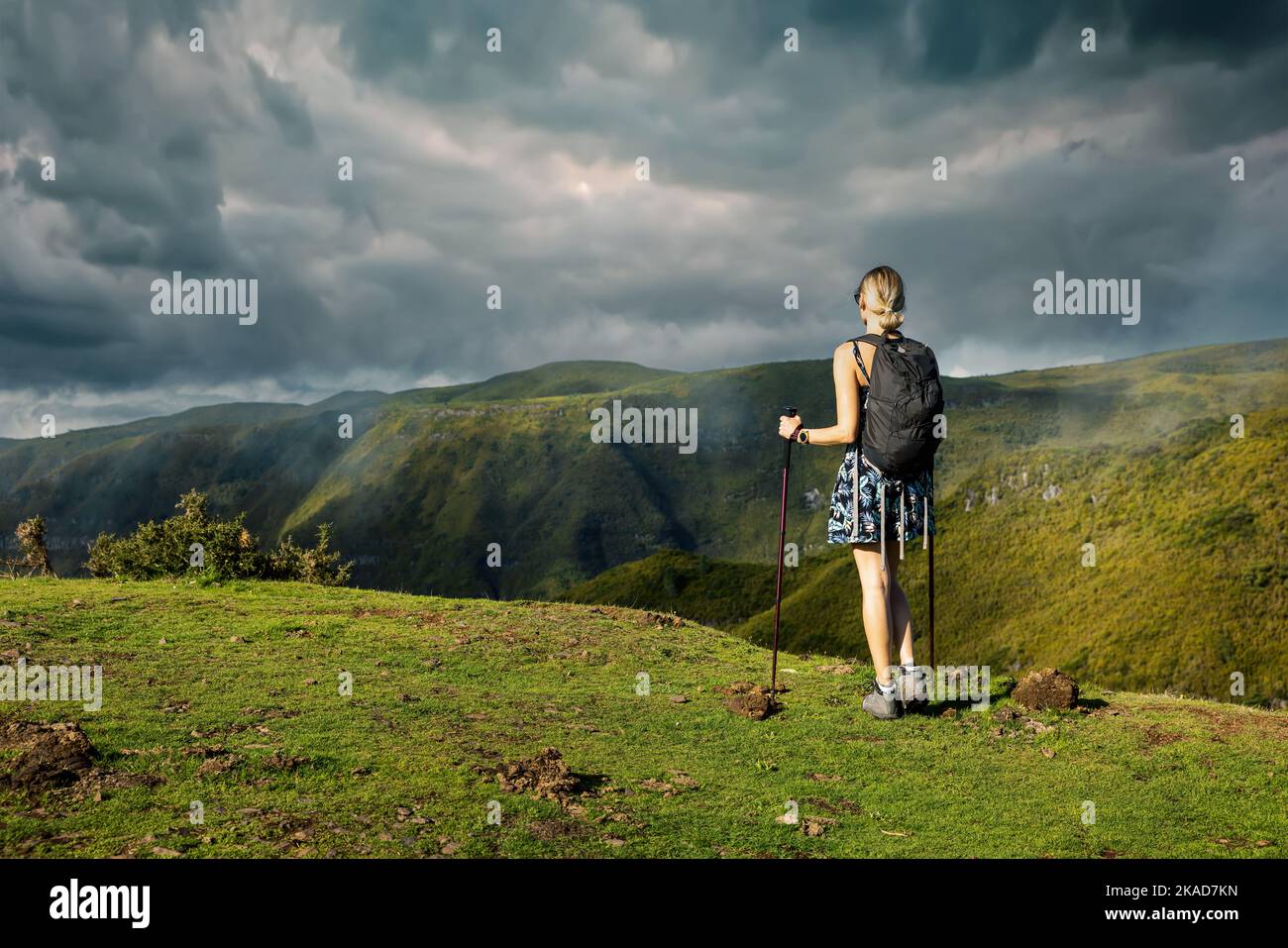 Junge Frau wandern in den Bergen. Genießen Sie schöne üppig grüne Landschaft mit dramatischen Himmel. Copy Space Stockfoto