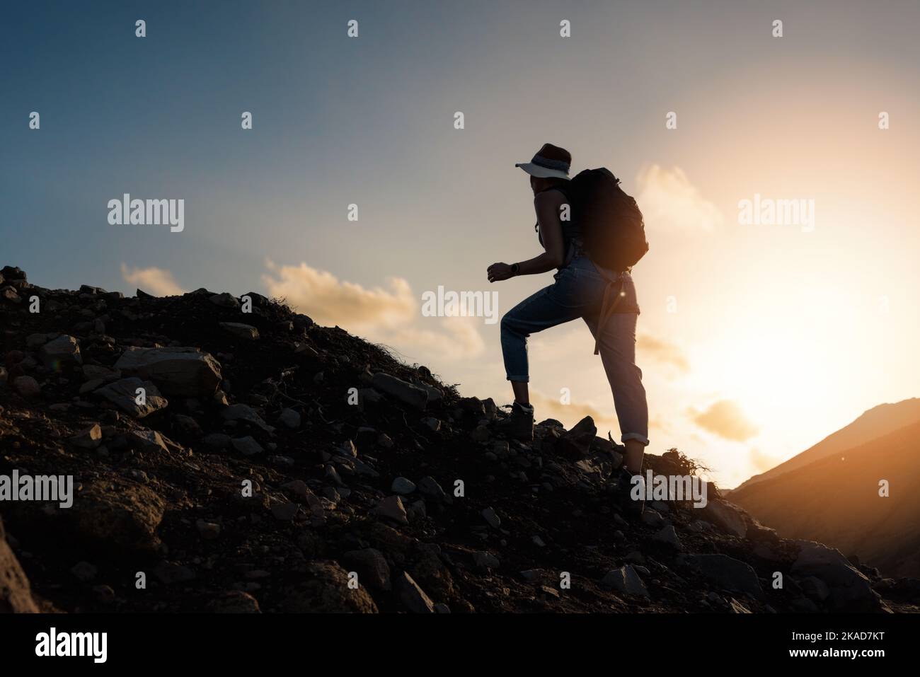 Frau steigt bei Sonnenaufgang auf den Berg. Motivation, Entschlossenheit und Leistungskonzept Stockfoto