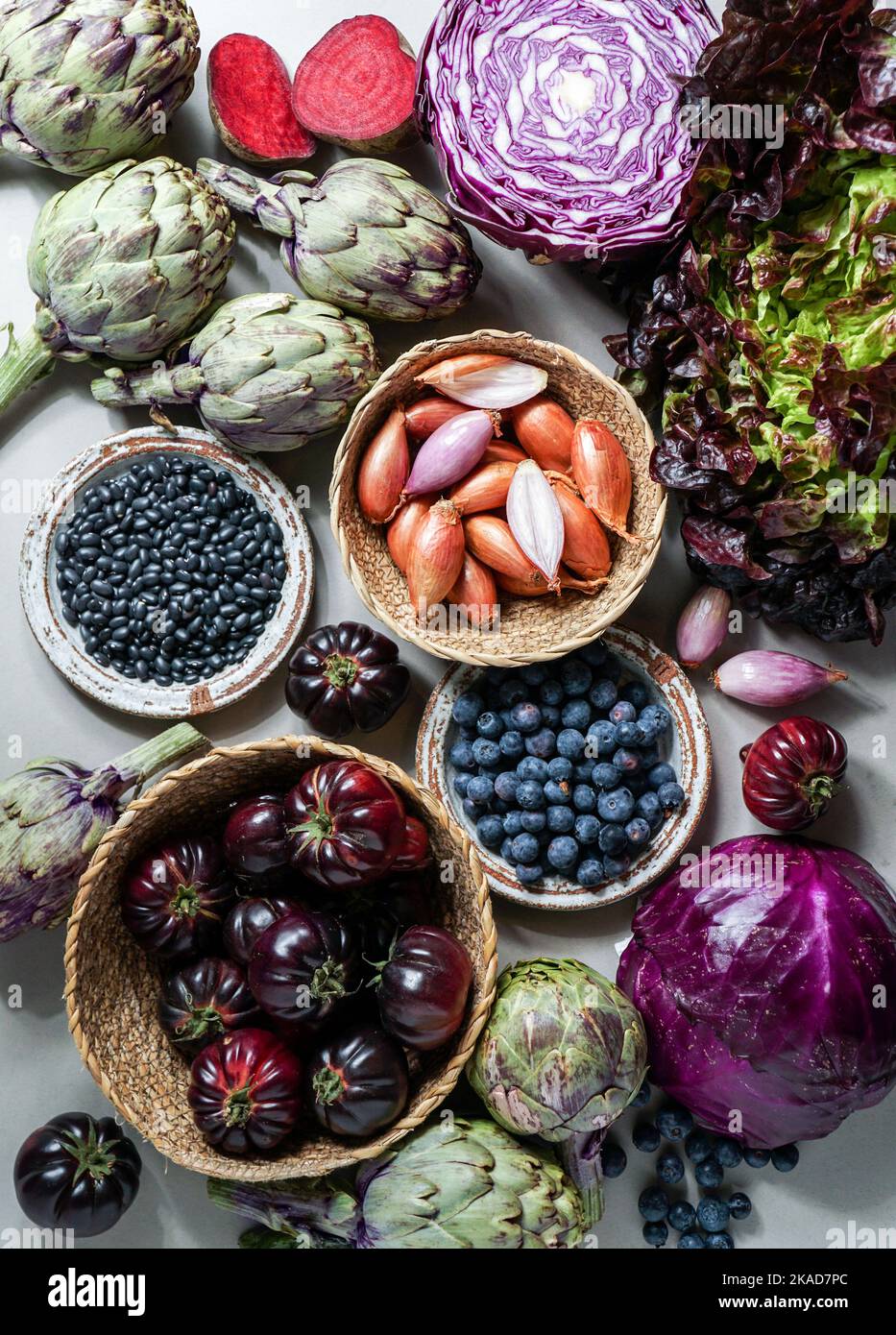 Lila und rot, violettes Gemüse auf dem violetten Hintergrund, Draufsicht. Lila Artischocke, Tomaten, Oniones, Heidelbeeren, Salat, Anthocynine enthalten, f Stockfoto