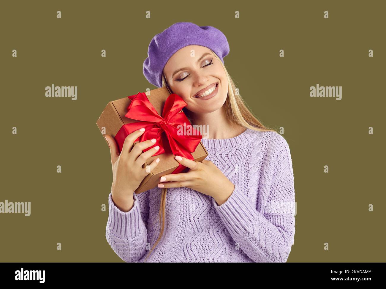 Glückliche blondy Frau mit geschlossenen Augen hält weihnachtsgeschenk-Box in den Händen und lächelt. Stockfoto