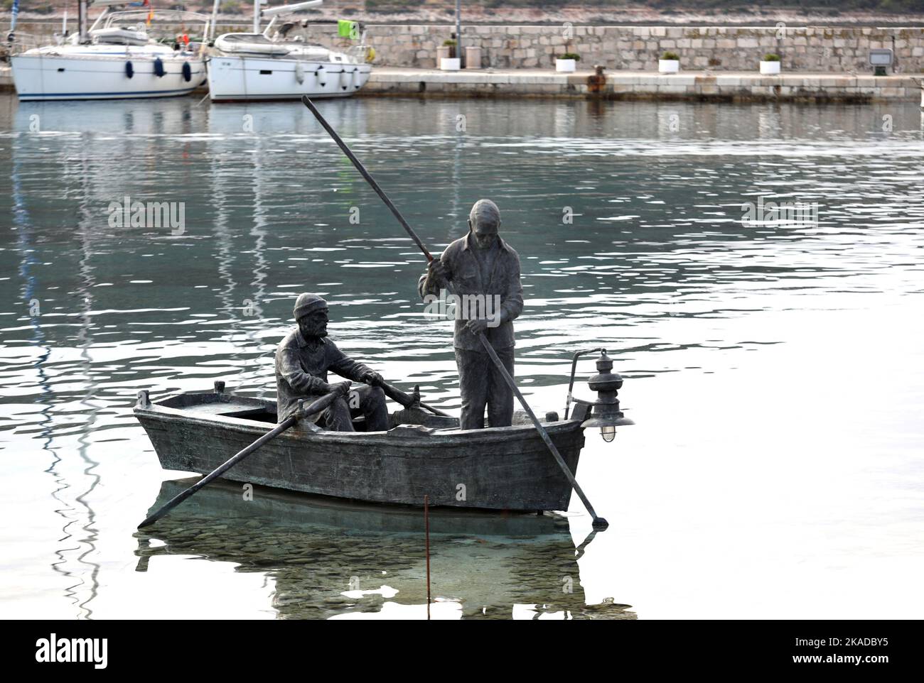 Am 02. November 2022 ist an der Meeresoberfläche in der Bucht des Hafens von Primosten in Primosten, Kroatien, ein Bronzestatue der Fischer zu sehen. Der Künstler Teo Baucic schuf ein attraktives Denkmal für zwei Fischer in einem Boot, die mit Rudern fischen. Die Wildtiere, die normalerweise nachts aufleuchtet, um Fische anzulocken, leuchten auch nachts auf diesem bronzenen Boot auf. Foto: Dusko Jaramaz/PIXSELL Stockfoto