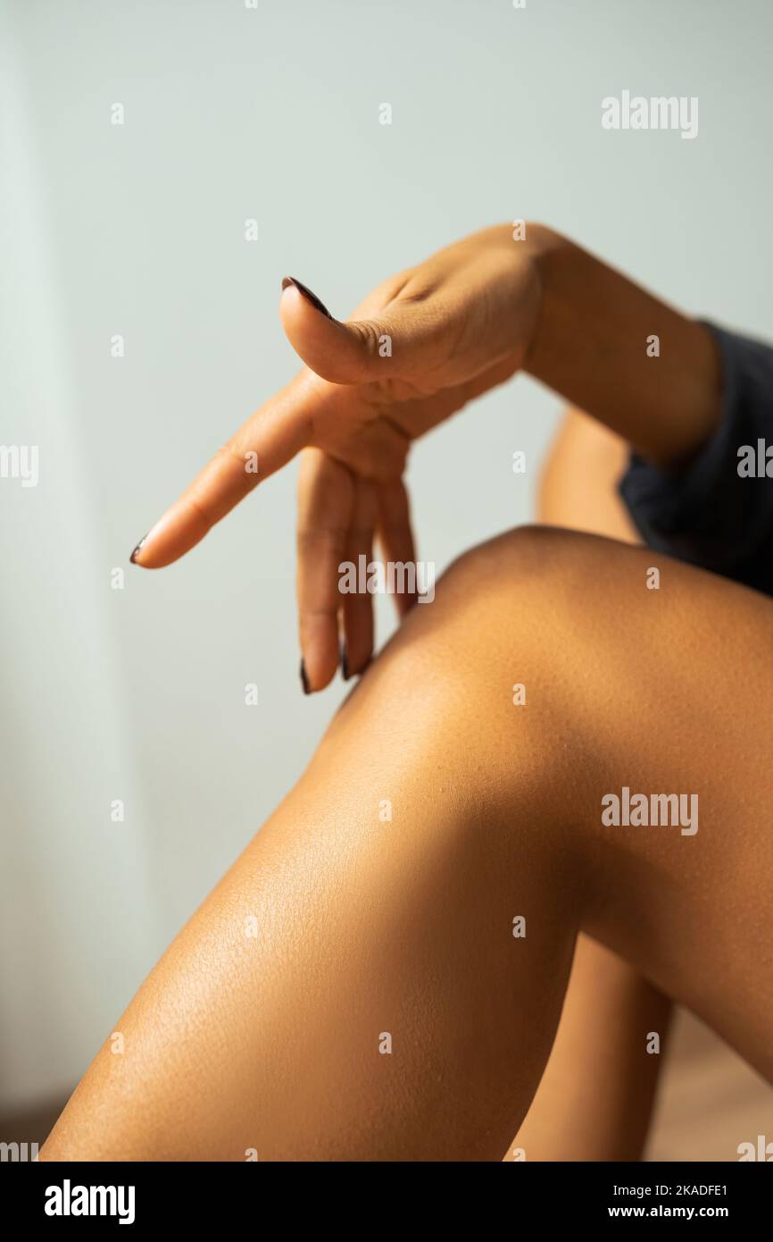 Beschnittene Ansicht einer afroamerikanischen Frau, die zu Hause das Knie berührt, Stockbild Stockfoto