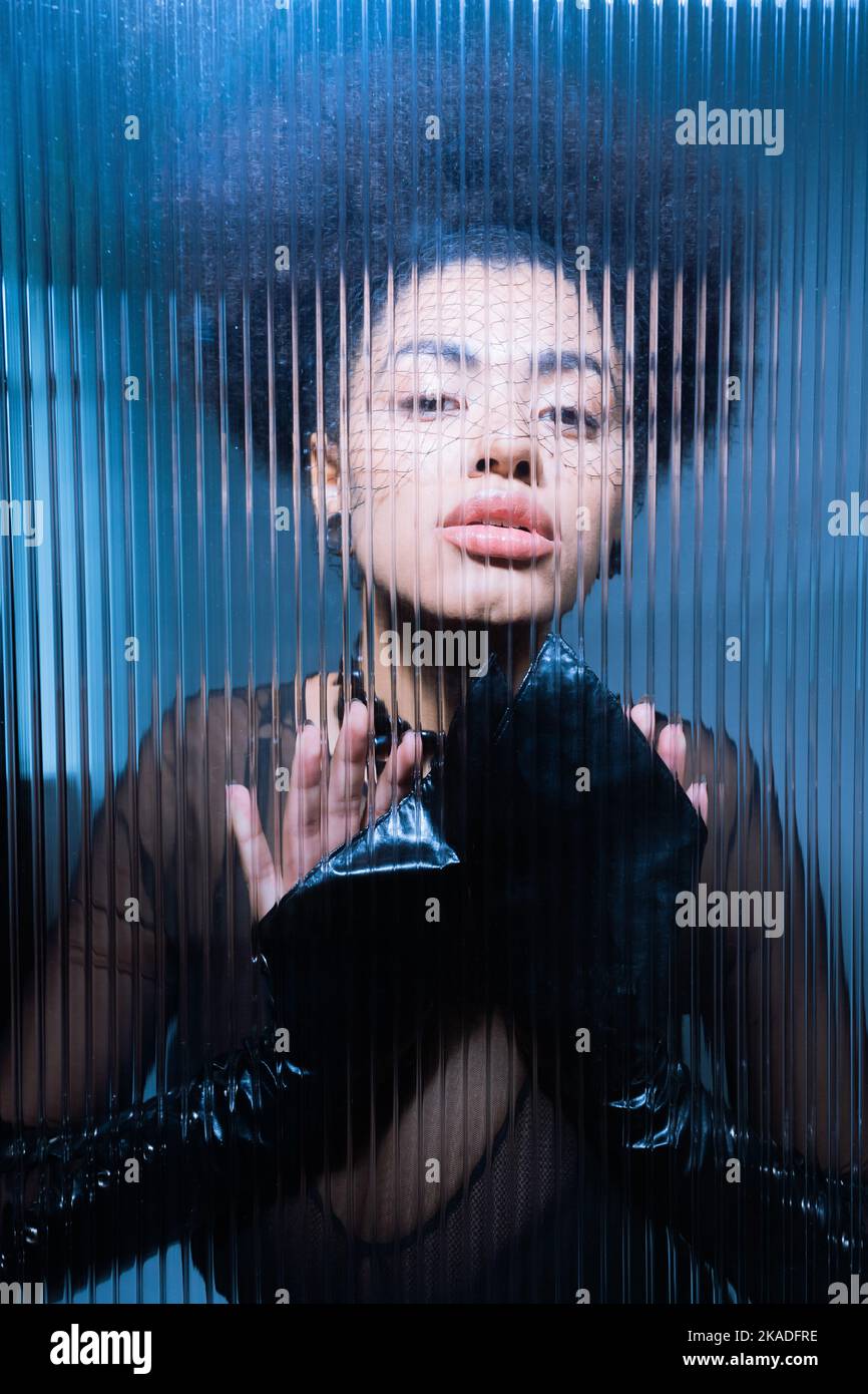 Junge afroamerikanische Frau in schwarzem Schleier Blick auf die Kamera durch zerzauste Glas, Stock Bild Stockfoto