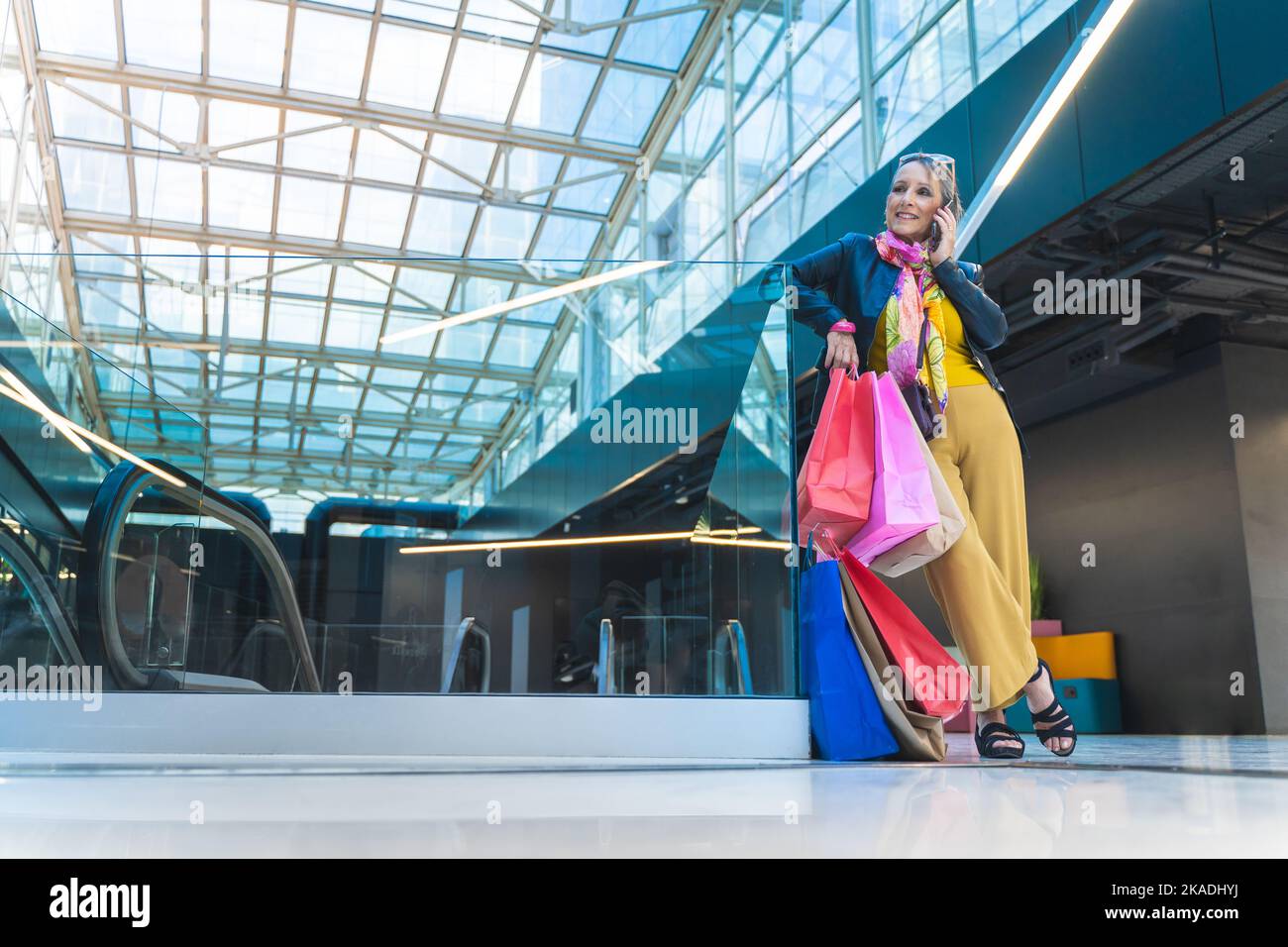 Reife Frau spricht Smartphone mit Einkaufstaschen in der Mall. Stockfoto