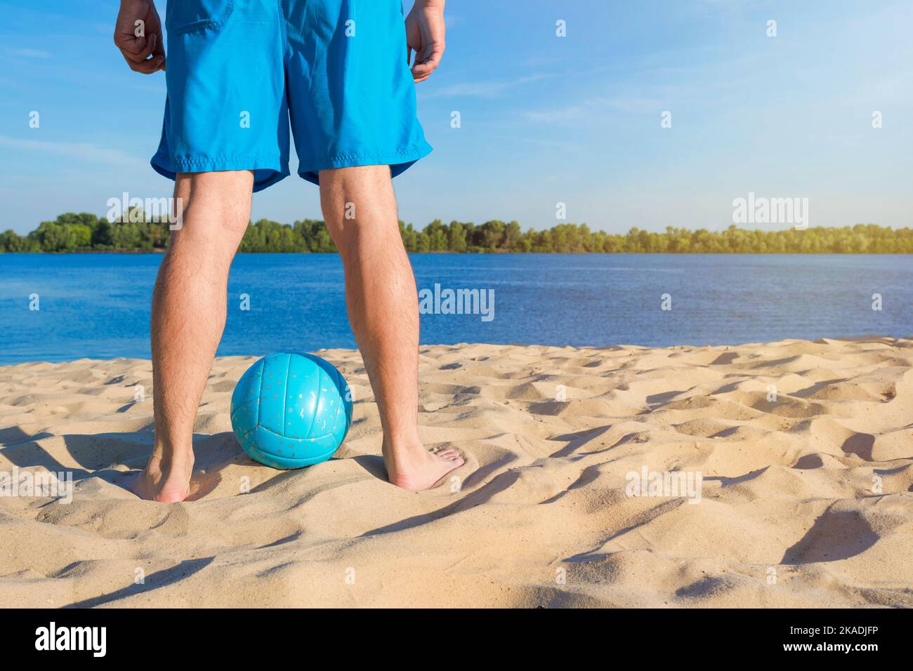 Eine Nahaufnahme eines Volleyballs und männlicher Beine am Strand. Gesundes Lifestyle-Konzept. Stockfoto