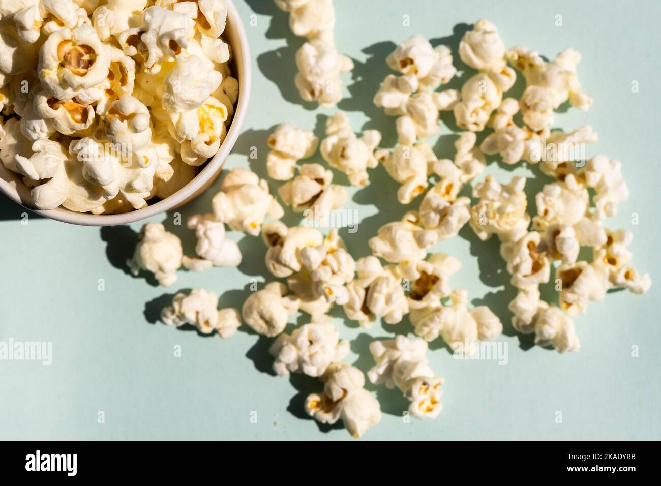 Verstreutes Popcorn aus dem Becher aus Bastelpapier. Konzept des Kinos oder Fernsehens. Stockfoto