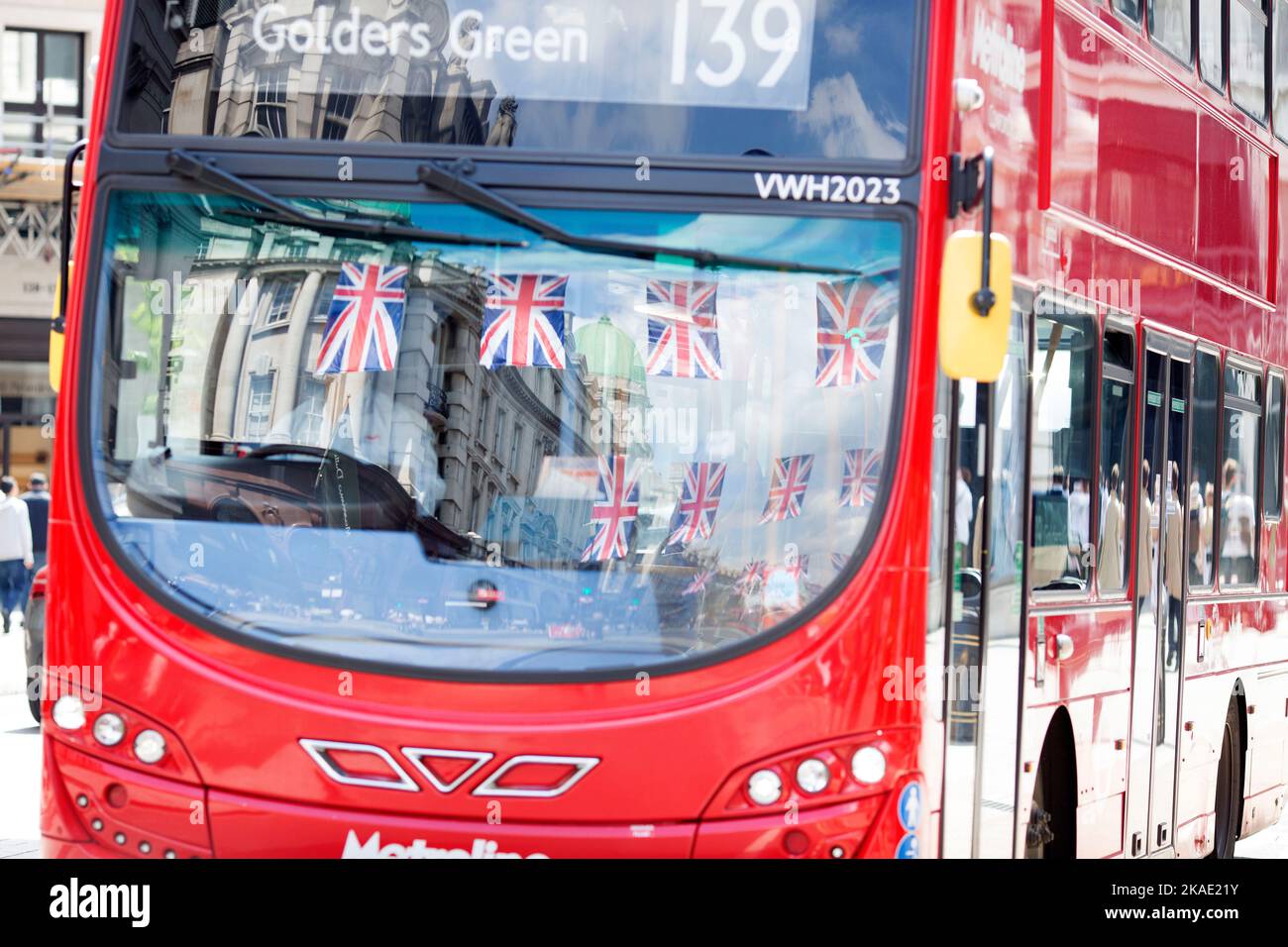 Fußgänger und die Dekoration der Unionsflagge spiegeln sich am ersten Tag des Platinum Jubilee Weekends in den Busfenstern im Zentrum von London wider. Stockfoto