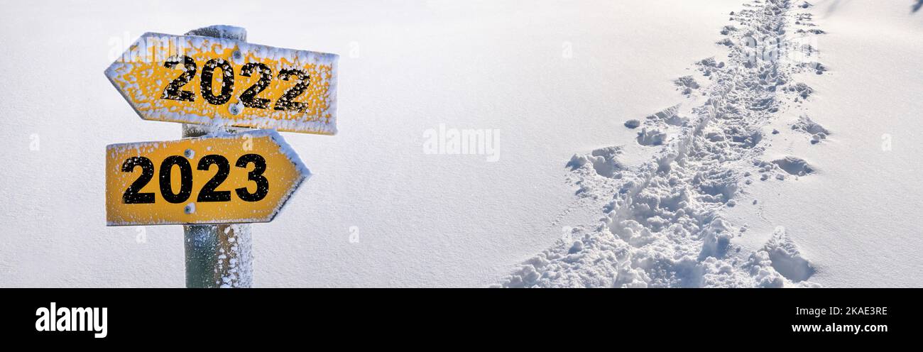 2022 und 2023 auf entgegengesetzten gelben Pfeilen auf Sow-Hintergrund mit Spuren in Panoramasicht geschrieben Stockfoto