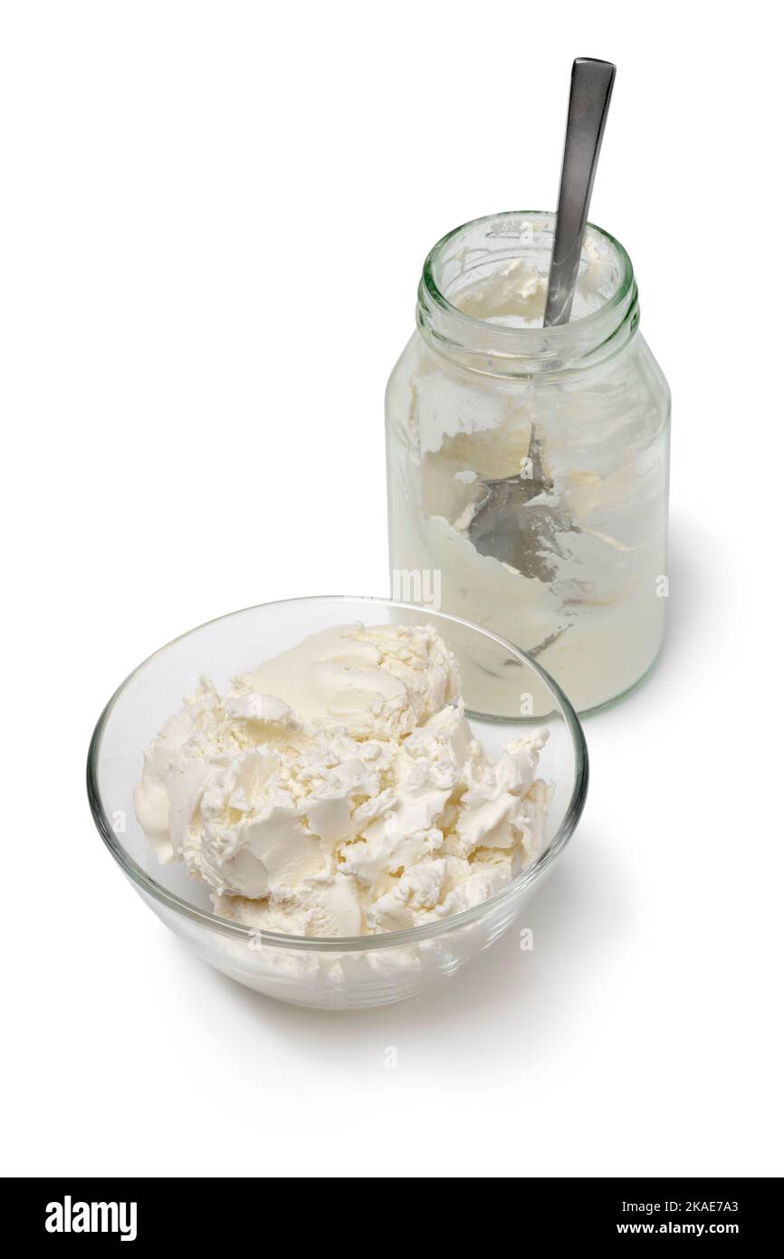Glasschüssel und Flasche mit gerinnter Creme Nahaufnahme isoliert auf weißem Hintergrund Stockfoto