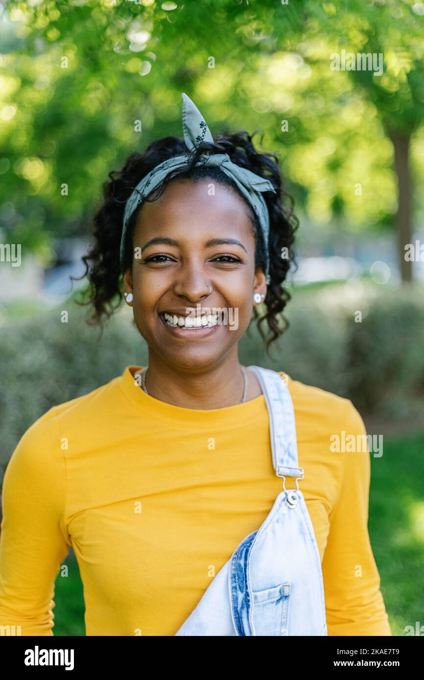 Lächelnde junge afroamerikanische Frau, die im Freien auf die Kamera schaut Stockfoto