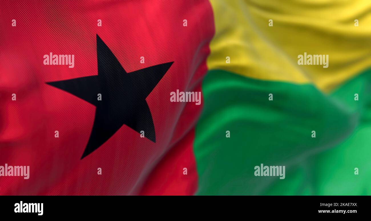 Nahaufnahme des Winkens der Nationalflagge von Guinea-Bissau. Die Republik Guinea Bissau ist ein westafrikanischer Staat. Texturierter Hintergrund aus Stoff. Selektiver Fokus Stockfoto