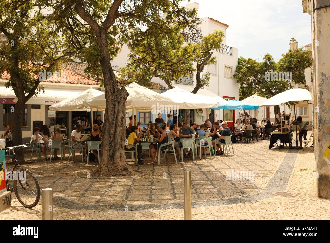 Menschen, die unter Sonnenschirmen vor einem Café sitzen, Lagos, Algarve, Portugal Stockfoto