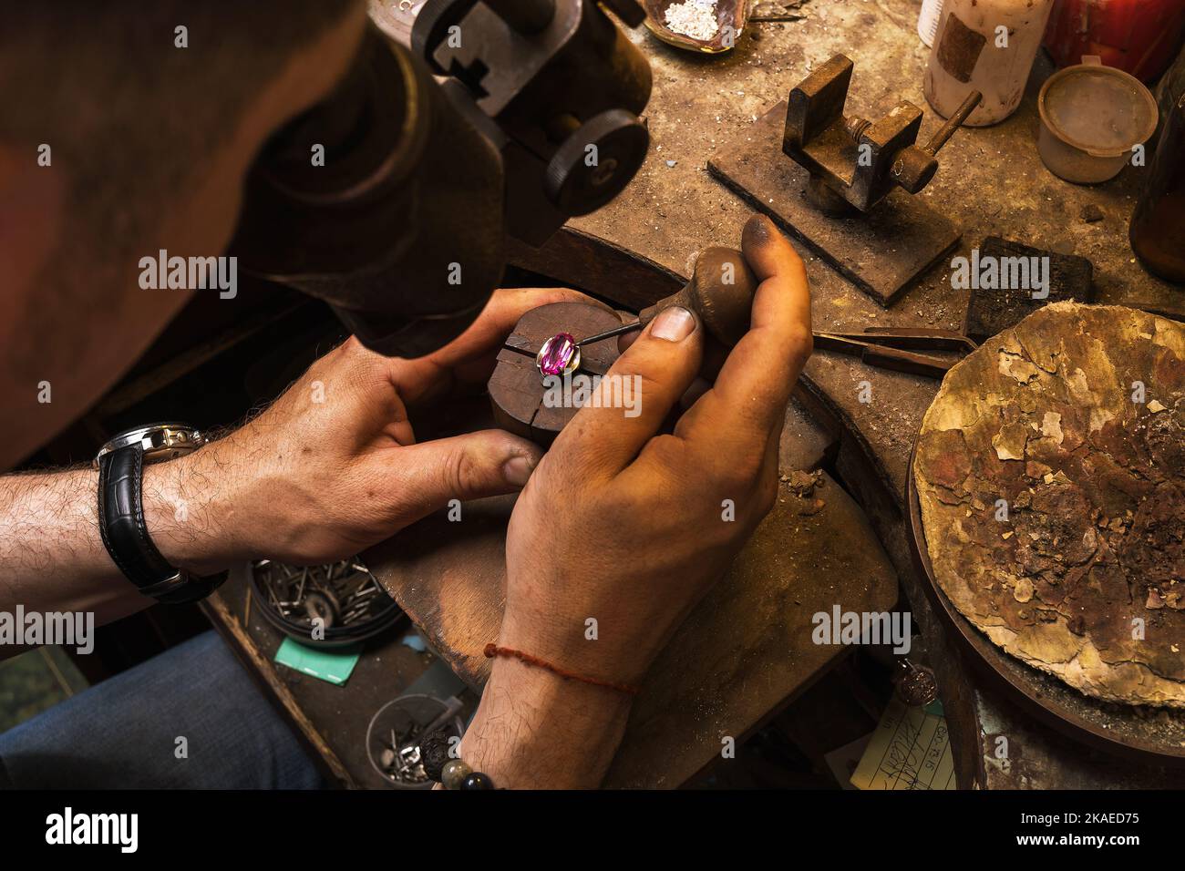 Der Juwelier nimmt einen Stein aus der Fassung eines Goldrings, um Schmuck zu reparieren Stockfoto