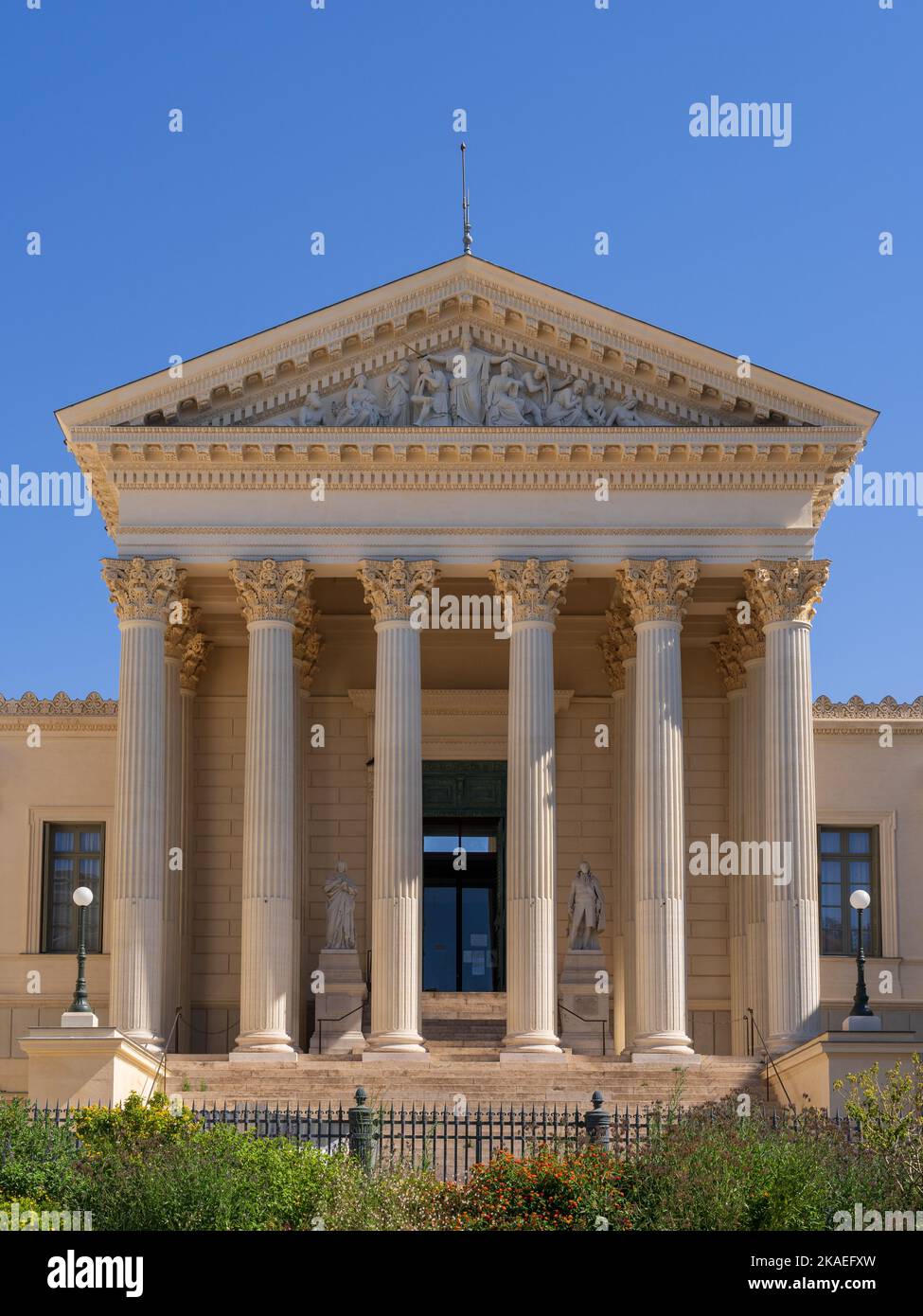 Vertikale Ansicht der neoklassizistischen Steinfassade mit Säulen und Giebel, die die Justiz des historischen Gerichtsgebäudes darstellen, Wahrzeichen von Montpellier, Frankreich Stockfoto