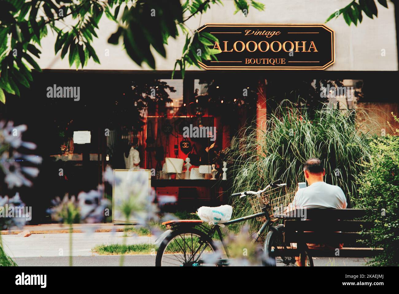 Ein Mann, der auf einer Bank vor der Vintage-Boutique Aloooooha in Shanghai sitzt Stockfoto