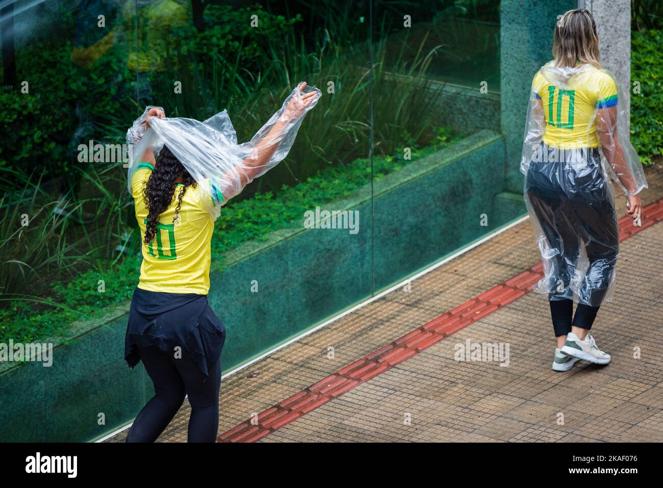 Brasilianische Frau, die sich auf dem Weg zu einem Bolsonaro-Protest in Belo Horizonte, Brasilien, mit einem Regenponcho zum Einwegartikel kleidet. Stockfoto