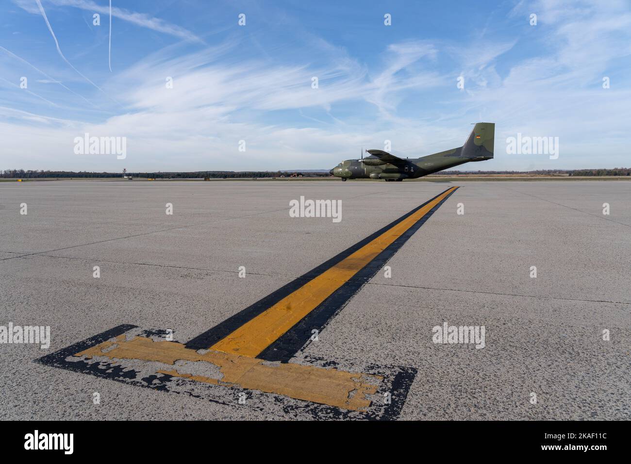 Eine Landebahn mit gelben Markierungen für den Piloten und das schwarze Militärflugzeug transall C160 im Hintergrund Stockfoto