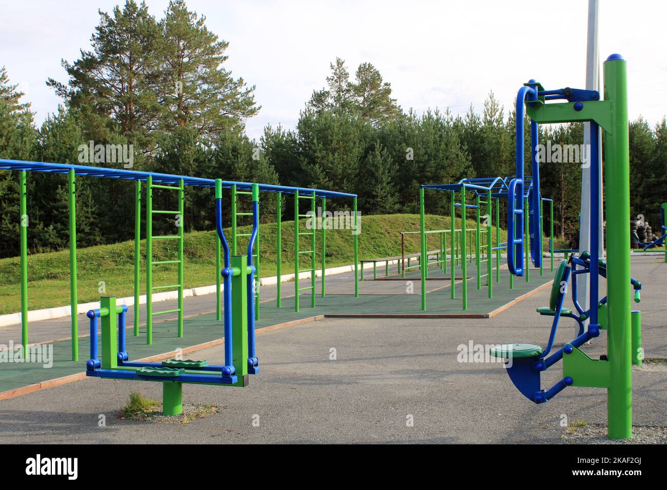 Sport-Straßenspielplatz mit Trainingsgeräten auf dem Hintergrund des Waldes. Das Konzept eines gesunden Lebensstils Stockfoto