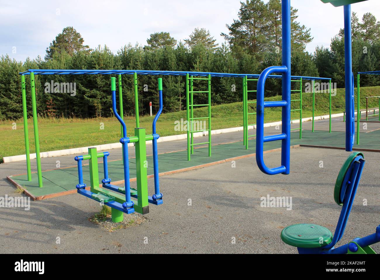 Sportplatz auf der Straße mit Trainingsgeräten vor dem Hintergrund eines grünen Waldes. Das Konzept eines gesunden Lebensstils Stockfoto