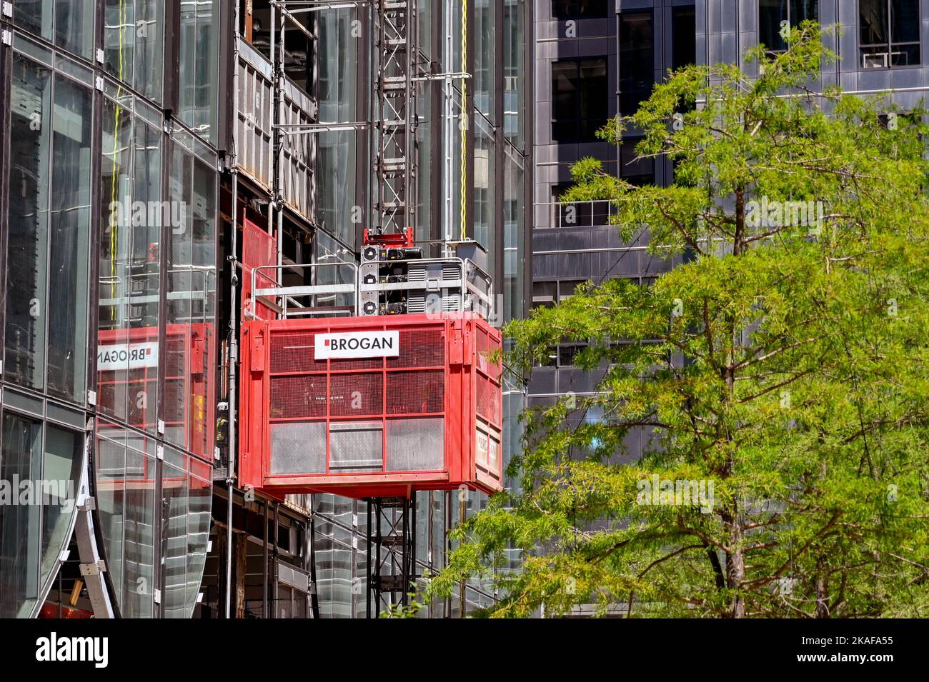 London, England - 2022. Juni: Bauarbeiter fahren mit einem Aufzug auf der Außenseite eines neuen Büroblocks, der im Bau ist Stockfoto