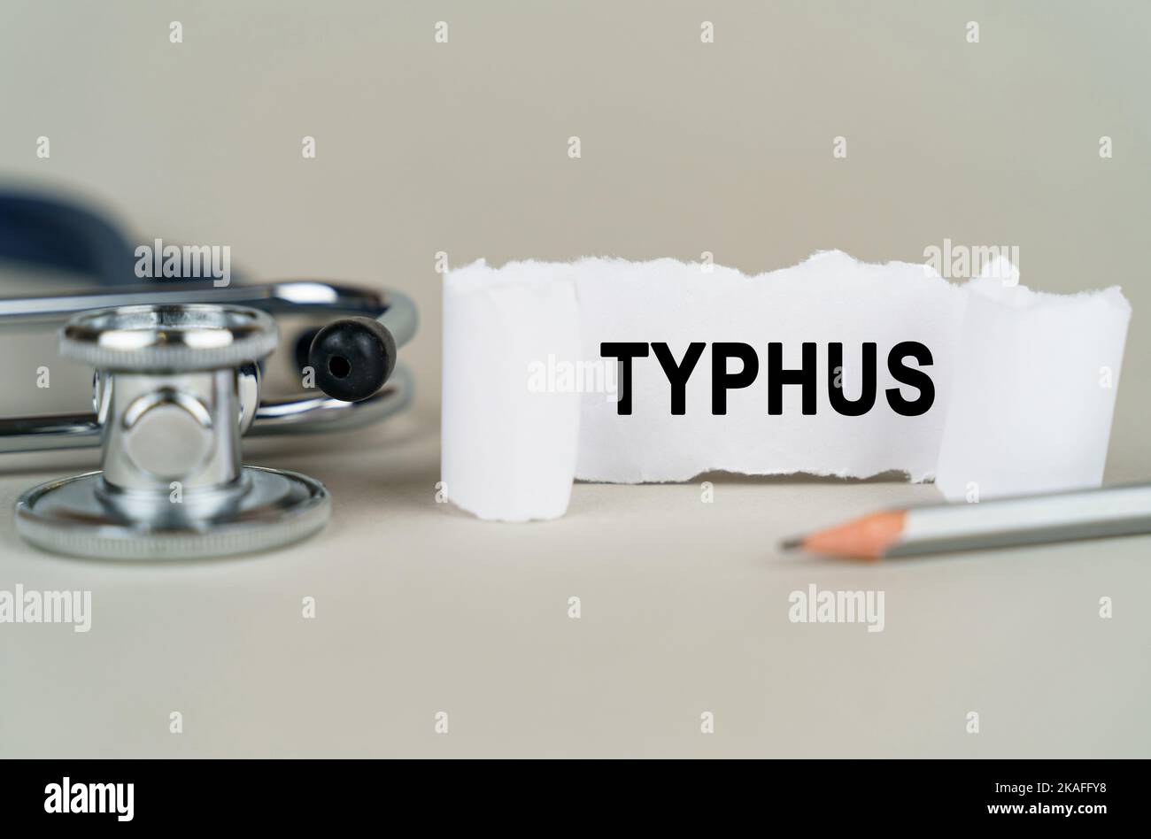Medizinisches Konzept. Auf grauem Hintergrund ein Stethoskop, ein Bleistift und ein Papierteller mit der Aufschrift - Typhus Stockfoto