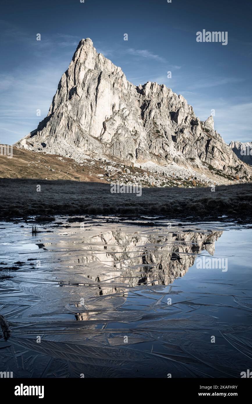 Die Felswand des Monte Ragusela spiegelte sich an einem frostigen Herbstmorgen am Giau-Pass in den Dolomiten, Italien, im Wasser und Eis eines Teiches wider Stockfoto