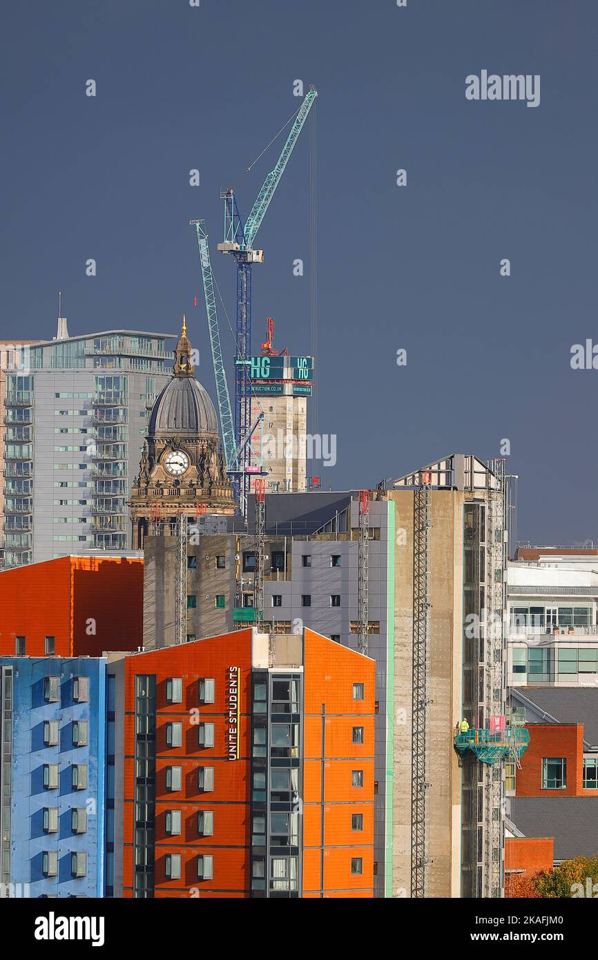 Ein lebendiges Foto des Stadtzentrums von Leeds mit dunklem Himmel. Die hohen Gebäude umgeben langsam den Uhrenturm des Rathauses von Leeds Stockfoto