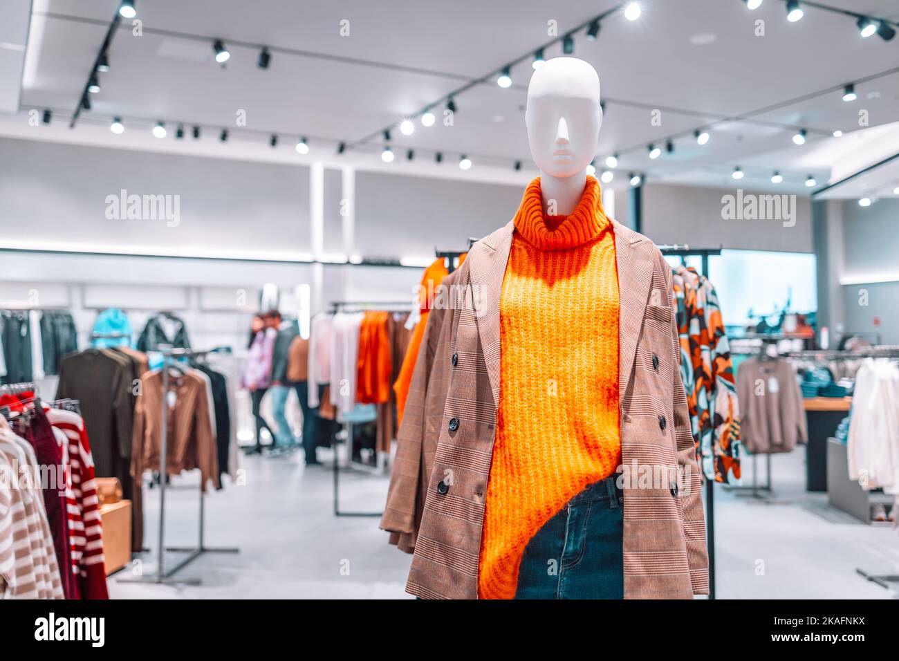 Schaufensterpuppe in einem leuchtend warmen orangefarbenen Pullover gekleidet, karierten Jacke Freizeitkleidung in einem Einkaufszentrum. Weibliche Schaufensterpuppen in einem Schaufenster. Stylisch neu Stockfoto