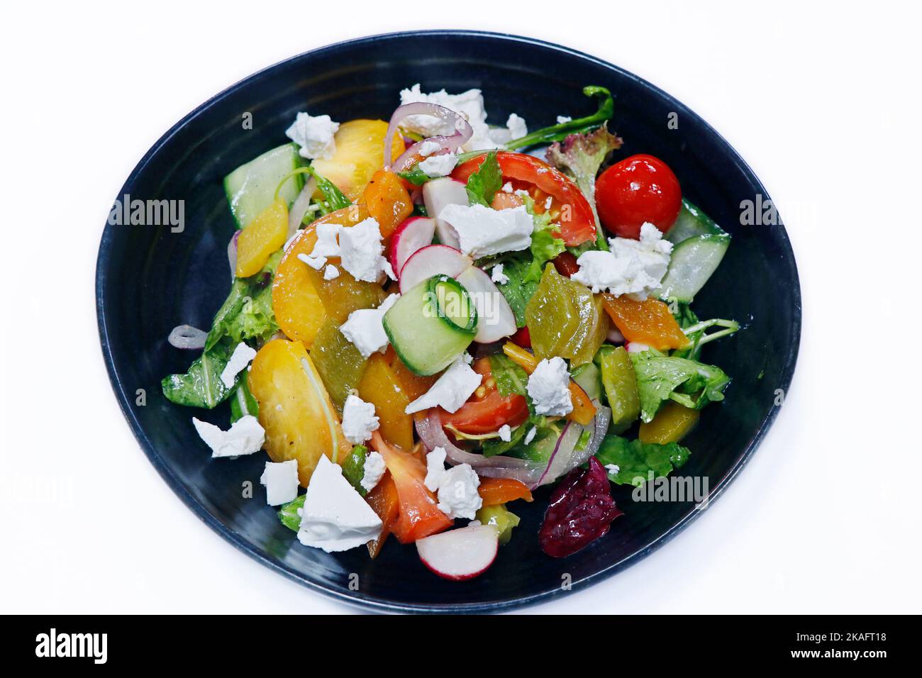 mediterraner griechischer authentischer Salat mit Feta-Käse-Krümel und Sommergemüse, Tomaten, Zwiebeln, Rettich und Blättern mit MinzolivolivDressing Stockfoto