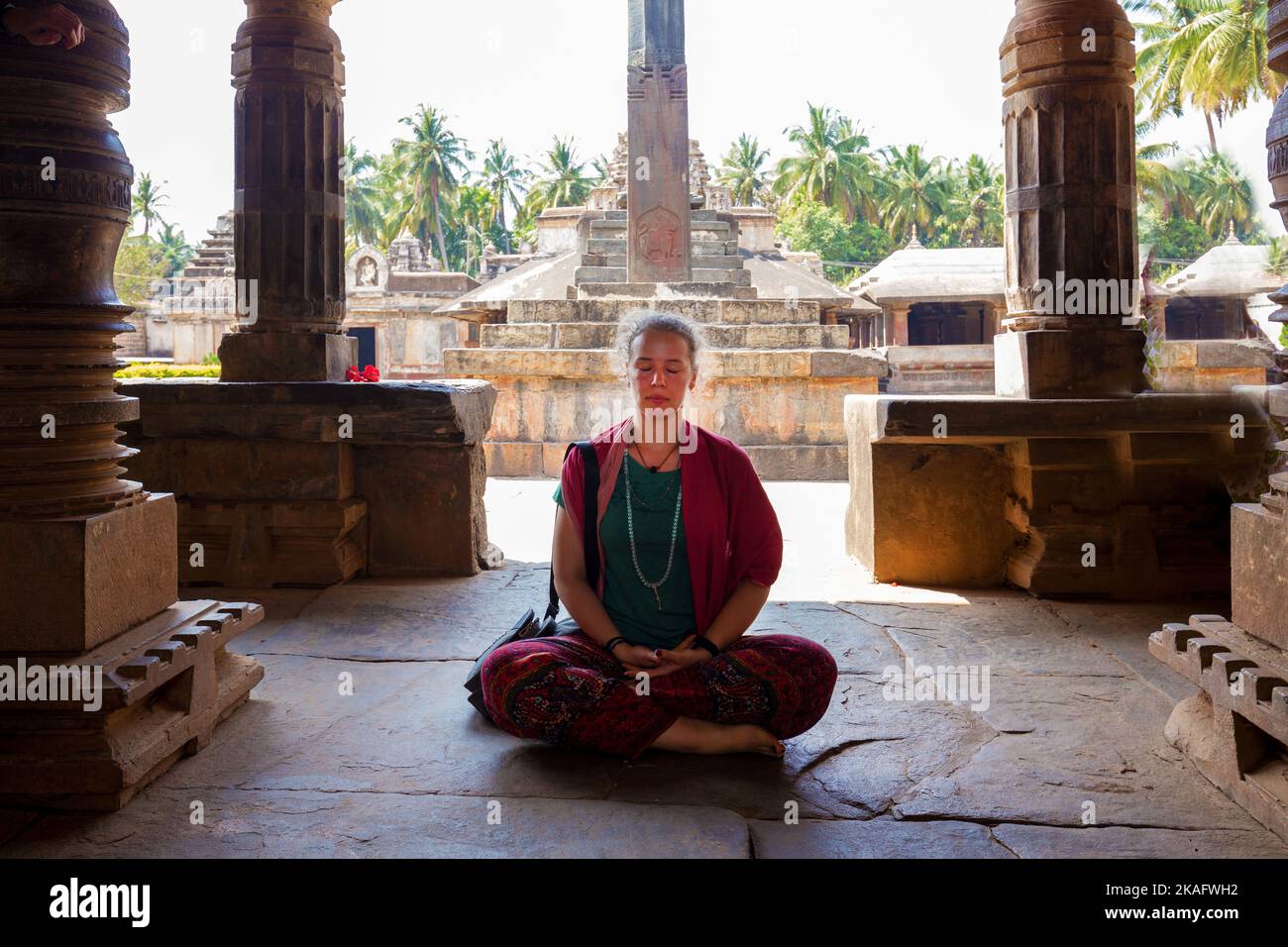 02-20-2019 Bonavasi (Karnataka), Indien. Europäische (österreichische) Yogalehrerin, die in der Pose von Lotos im alten Madhukeshvara-Tempel sitzt. Hinter - pa Stockfoto