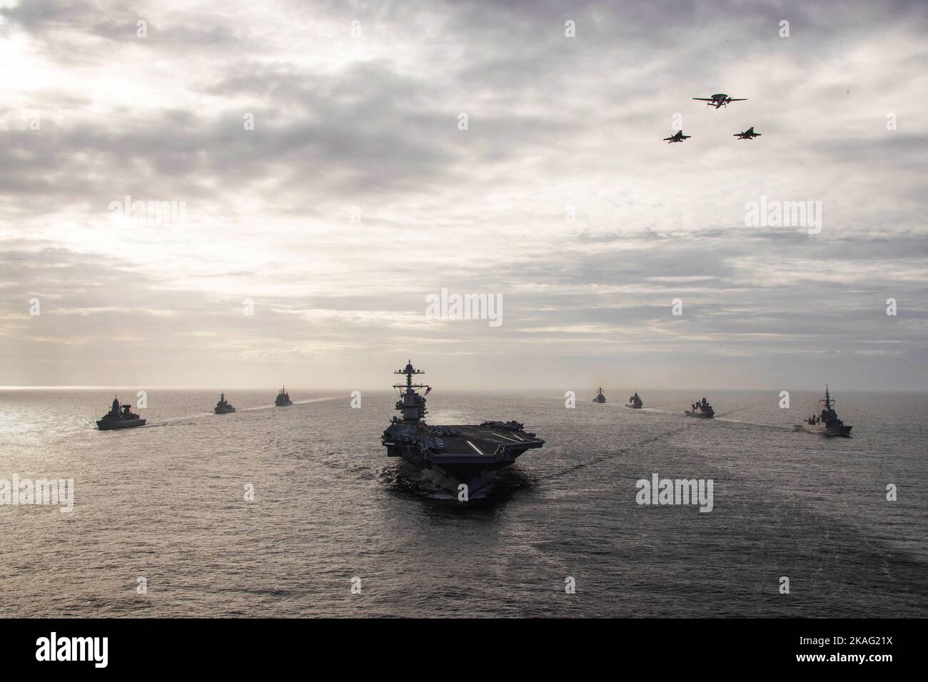Auf See. 25. Oktober 2022. An Carrier Air Wing (CVW) 8 angeschlossene Flugzeuge fliegen über den erstklassigen Flugzeugträger USS Gerald R. Ford (CVN 78), während das Schiff in Formation mit der spanischen Armada Fregatte Ãlvaro de BazÃn (F 101), der dänischen Fregatte HDMS Peter Willemoes (F362), der niederländischen Fregatte HNLMS De Zeven Provincien (F 802) dampft, Arleigh Burke-Klasse, USS Ramage (DDG 61), die deutsche Fregatte FGS Hessen (F 221), die niederländische Fregatte HNLMS Van Amstel (F 831) und der Ticonderoga-Klasse, USS Normandy (CG 60), 25. Oktober 2022. Die Gerald R. Ford Carrier Strike Group (GRFCSG) ist Stockfoto