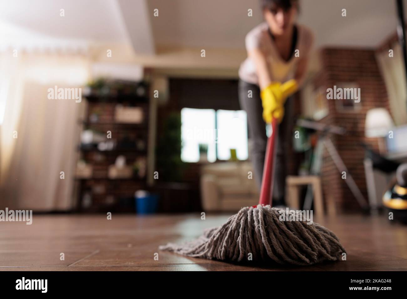 Hausmädchen Reinigung Boden mit Mopp tragen Reinigungshandschuhe, Abschluss Reinigung Wohnung für Kunden. Weibliche Hausangestellte, die ihre Arbeit mit Hingabe und Haushaltung erledigt. Stockfoto