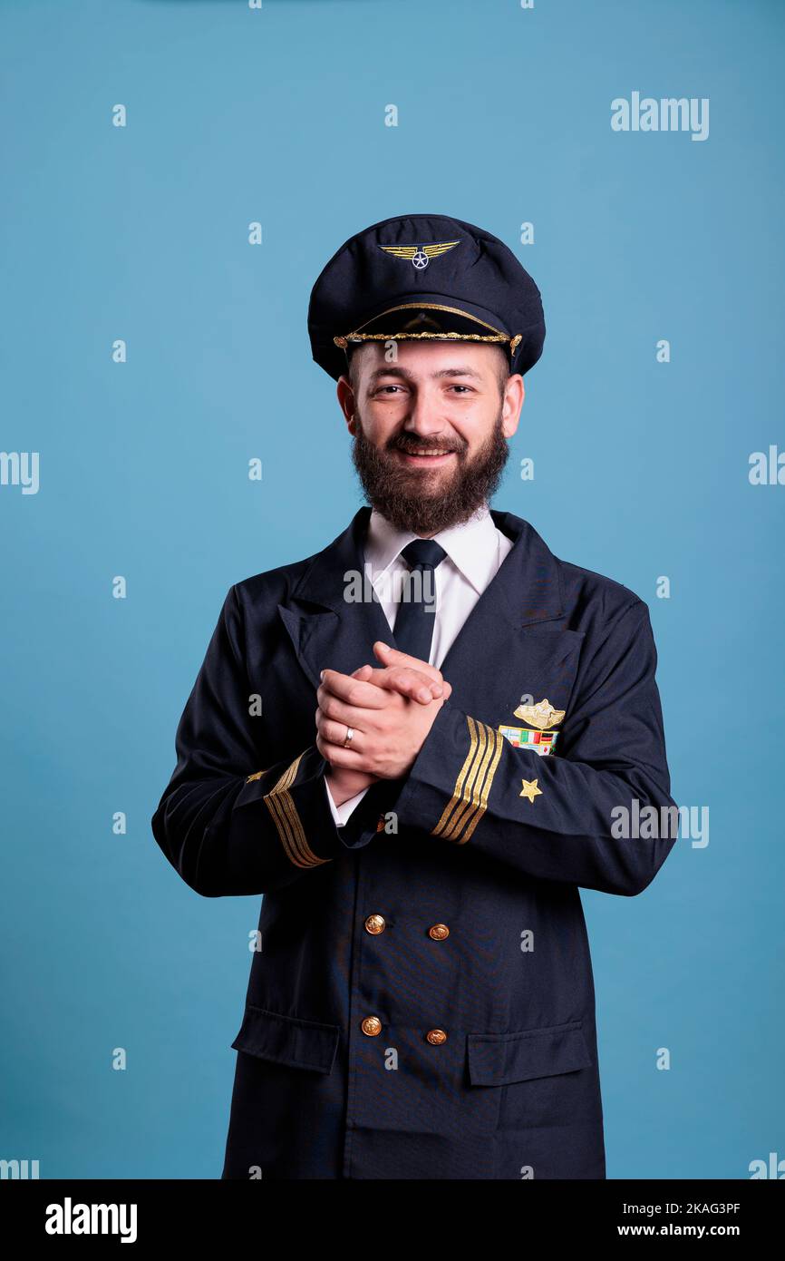 Lächelnd aufgeregt Flugzeug Pilot in professionellen Uniform klatschen Hände. Glücklicher, positiver Kapitän der Flugbahn applaudiert, Handflächen schüttelnd, stehend, Kamera anblickend, mittellange Aufnahme im Studio Stockfoto