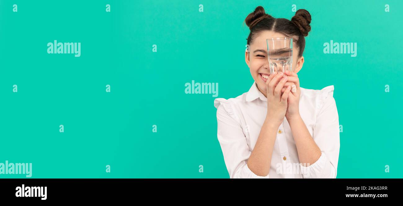 Kind hält ein Glas Mineralwasser. Kind hat Durst. Kindergesicht, horizontales Poster, Teenager-Mädchen isoliertes Porträt, Banner mit Kopie Stockfoto