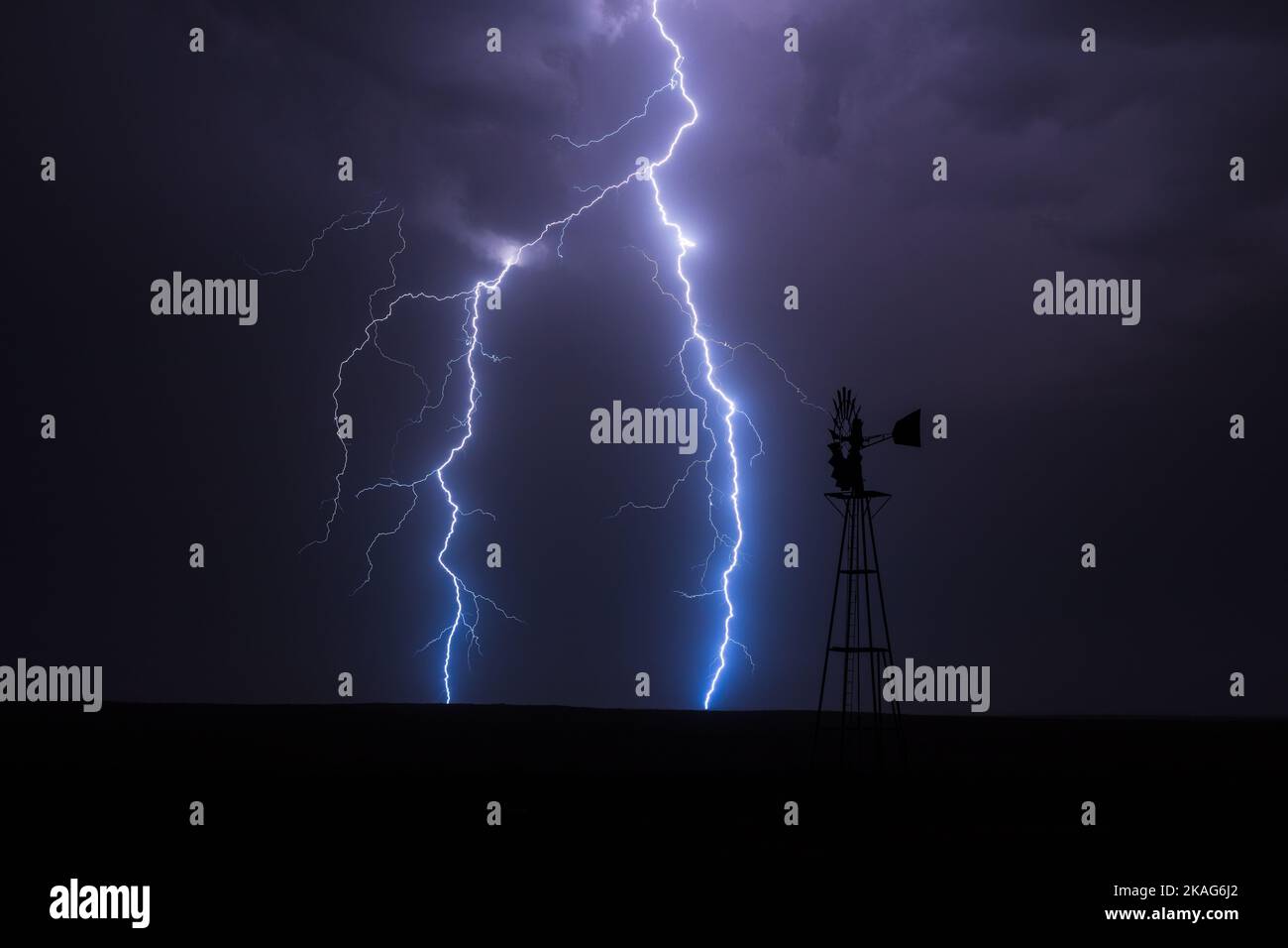 Bei einem starken Gewitter in der Nähe von Springfield, Colorado, schlägt ein Blitz hinter einer Windmühle ein Stockfoto