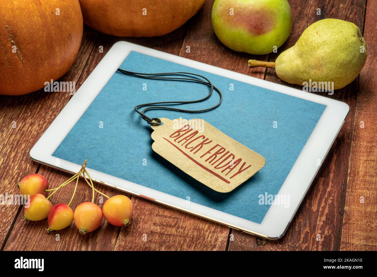 Black Friday Sale sign - ein Papierpreisschild auf einer digitalen Tablette, umgeben von Früchten und Kürbis Stockfoto