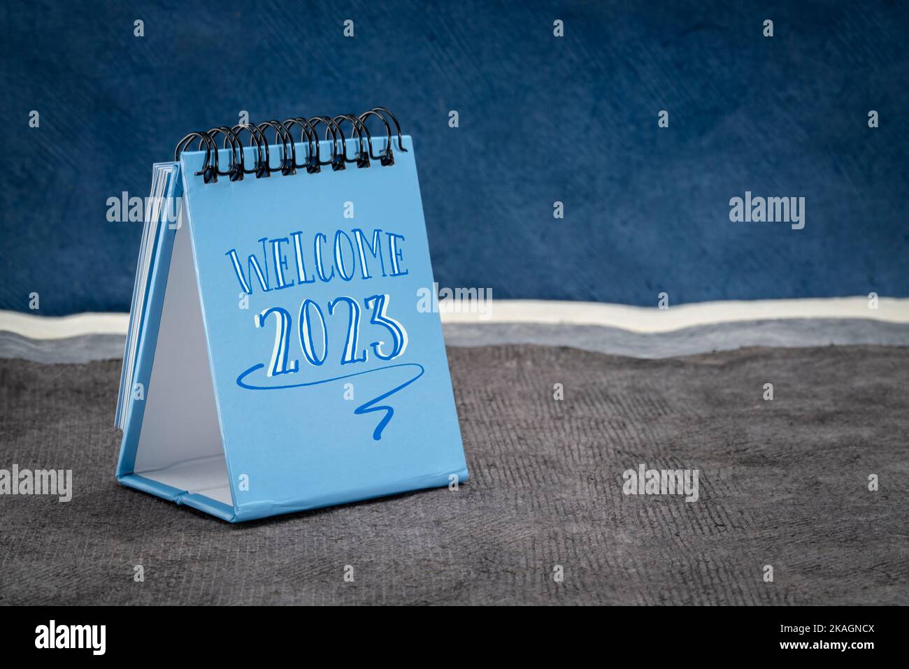 Willkommen 2023 - Handschrift in einem Desktop-Kalender gegen abstrakte Papierlandschaft, Neujahrskonzept Stockfoto