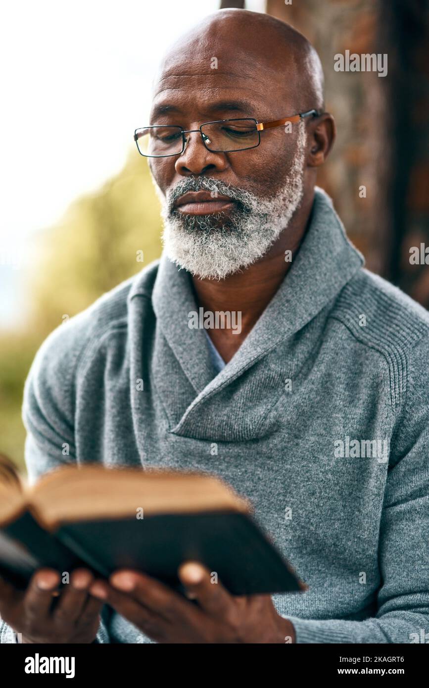 Lesen Sie mehr, sorgen Sie sich weniger. Ein Mann, der draußen ein Buch liest. Stockfoto
